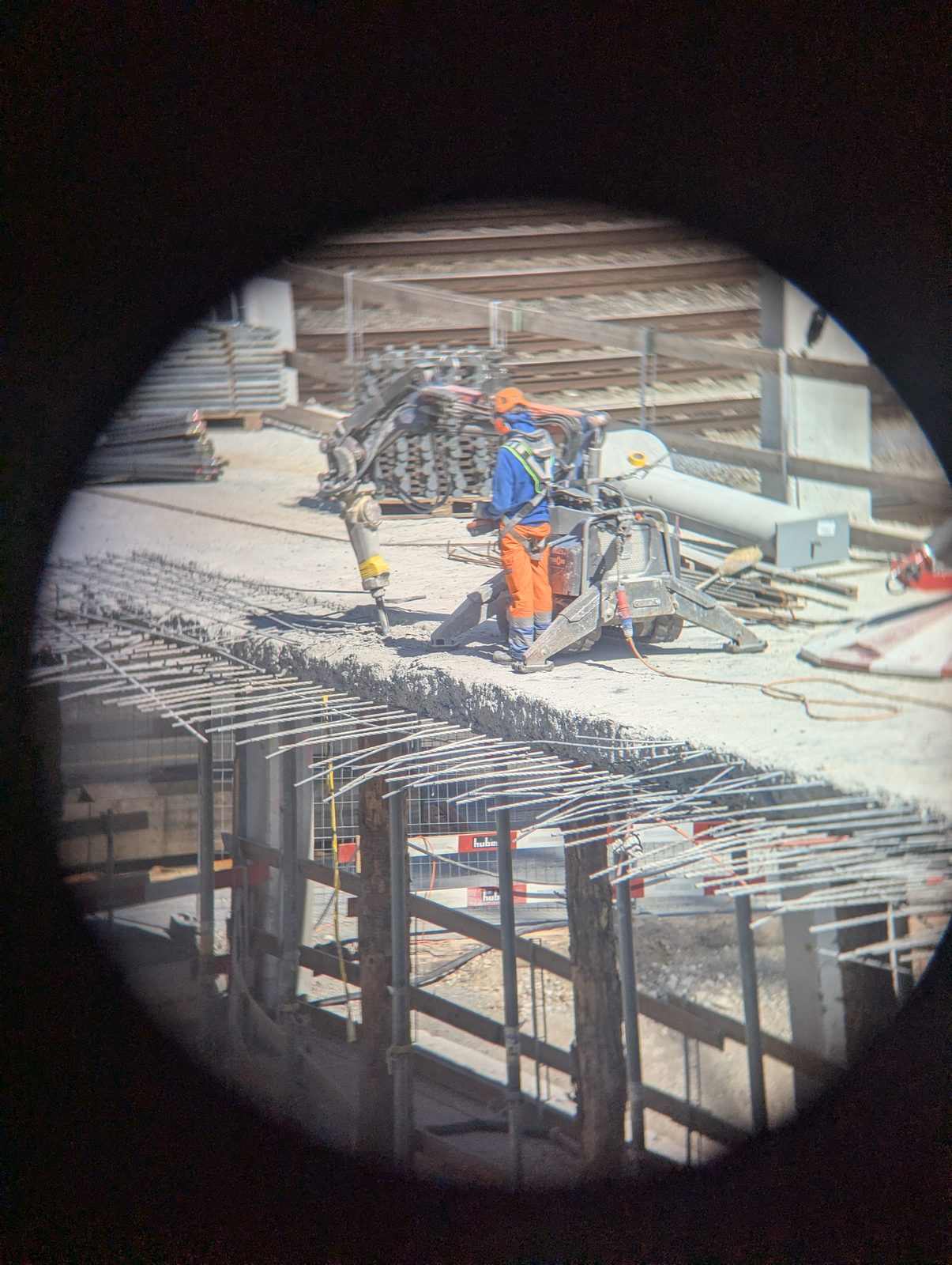 Construction worker with a breaker machine, seen through a tube